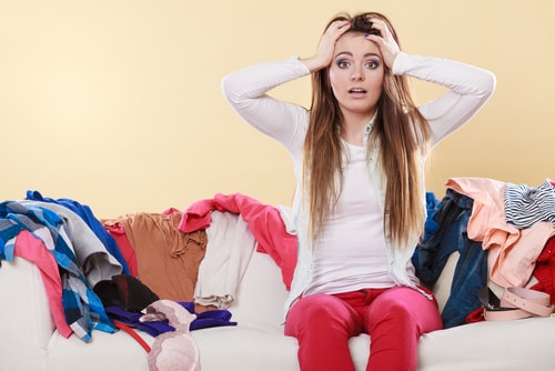 Desperate helpless woman sitting on sofa couch in messy living room