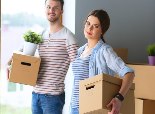 Happy young couple packing boxes and moving into a new home